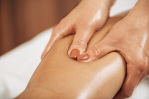 Lymphatic drainage massage. Hands of a masseuse massaging leg of a female client