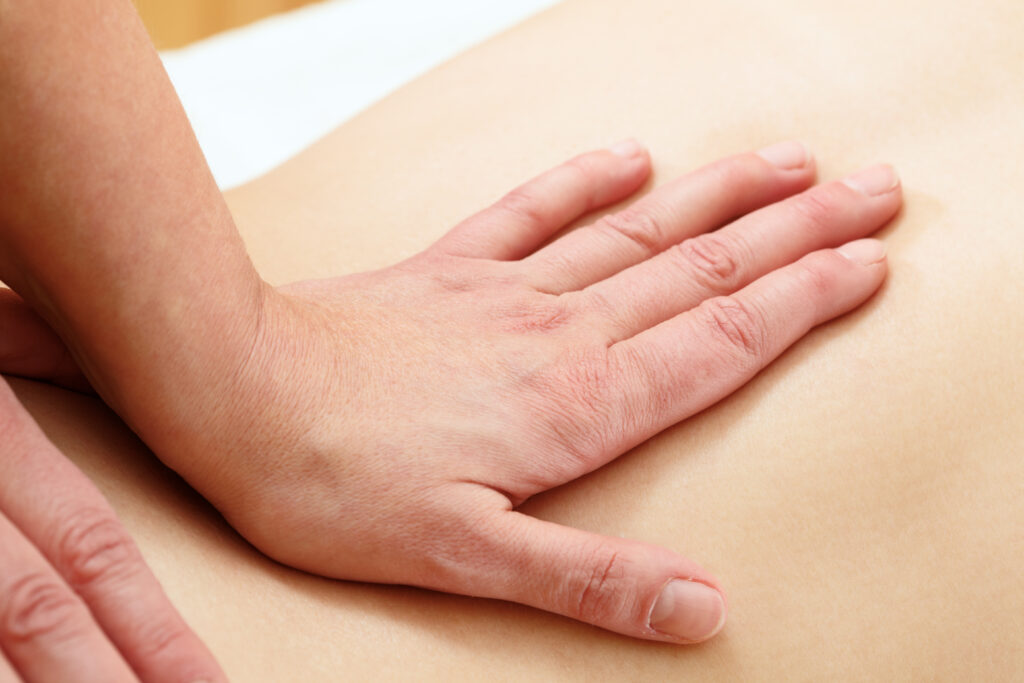 cranial sacral massage; therapist's hands on the subject in action; slight pressure on the lumbal and sacral regions